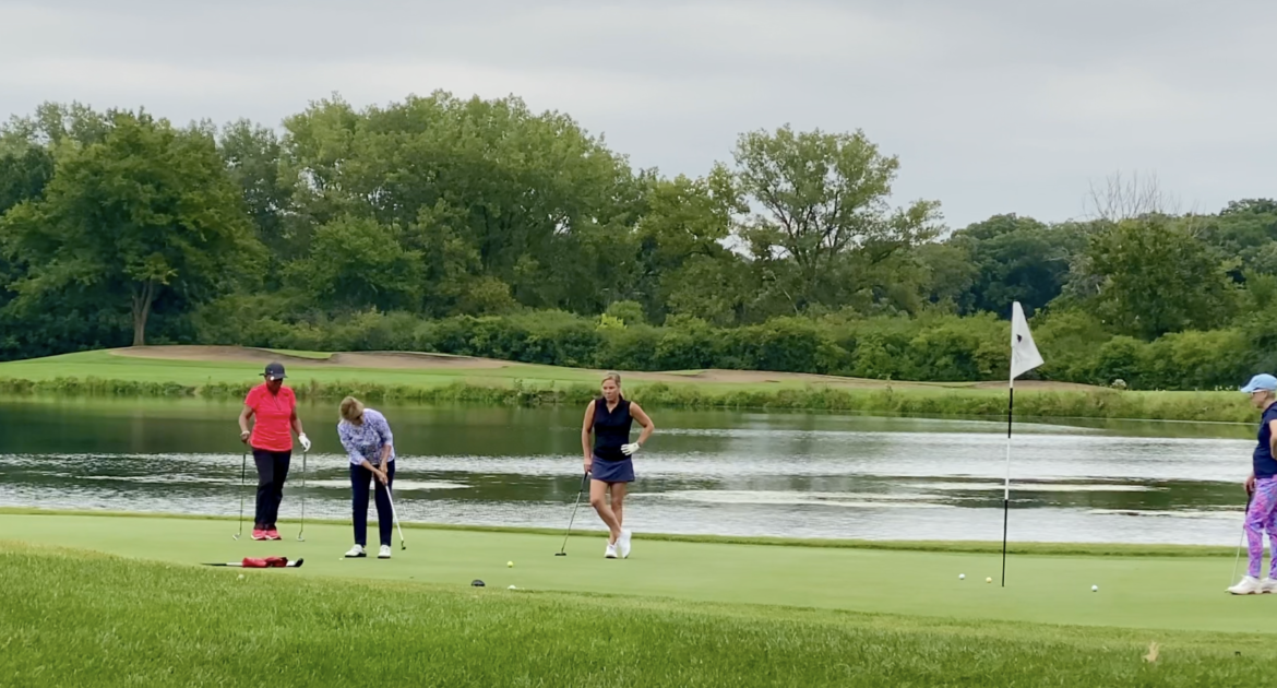 4 women golfing on a forest preserve golf course in front of a lake